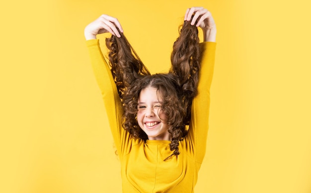 Enlouquecendo menina feliz com cabelo longo ventoso cabelo saudável e forte bom shampoo ou loção cabeleireiro salão de beleza Conceito de cabelo forte e saudável Criança pequena cabelo comprido brincando por aí