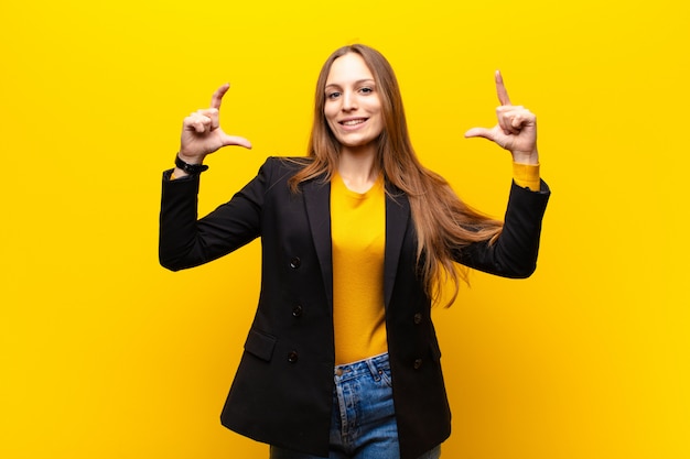 enmarcando o esbozando su propia sonrisa con ambas manos, luciendo positiva y feliz