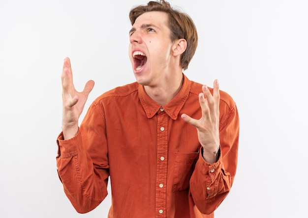 Enojado mirando hacia arriba joven guapo con camisa roja extendiendo las manos