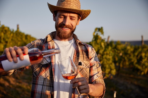 Enólogo alegre derramando vinho na fazenda