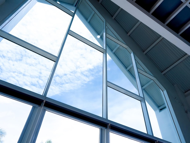 La enorme estructura de la ventana de vidrio en la casa a dos aguas Ventana grande de vidrio transparente debajo del techo con una vista del cielo azul afuera Diseño y construcción de interiores de casas y edificios modernos