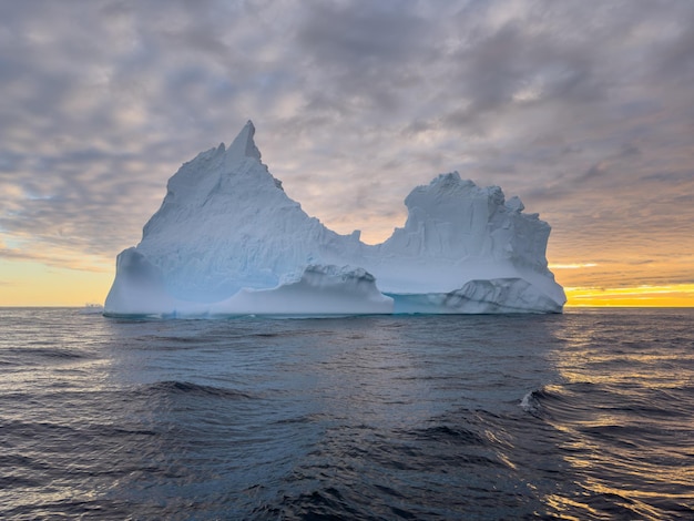 Foto un enorme glaciar desprendido se desvía en el océano sur frente a la costa de la antártida al atardecer.