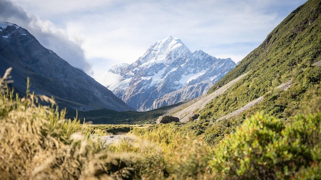 Foto una enorme montaña nevada con un glaciar que se eleva sobre el pintoresco valle alpino del monte cook, nueva zelanda