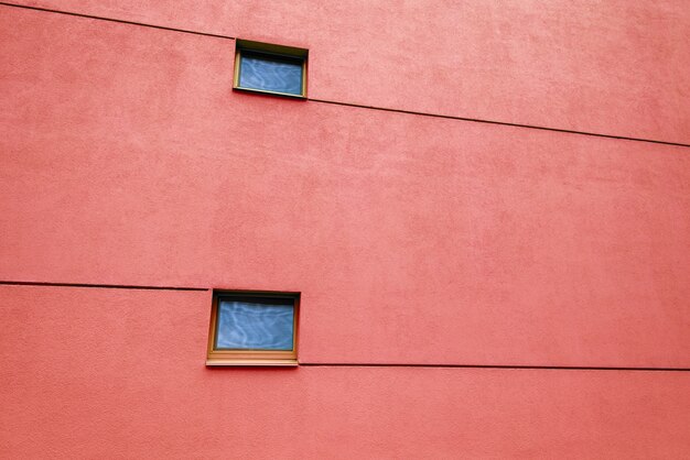 Enorme pared roja en un edificio moderno con dos ventanas y líneas. Reflejos en ventanas. Copia espacio