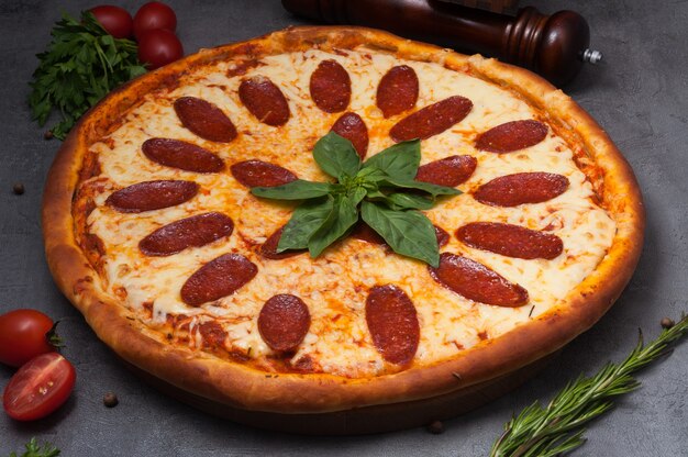 Enorme pizza de pepperoni con queso mozzarella decorada con albahaca