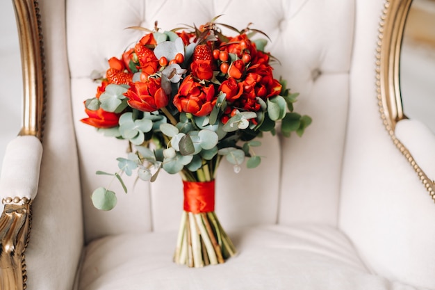 Un enorme ramo de hermosas rosas rojas con fresas se encuentra en la silla