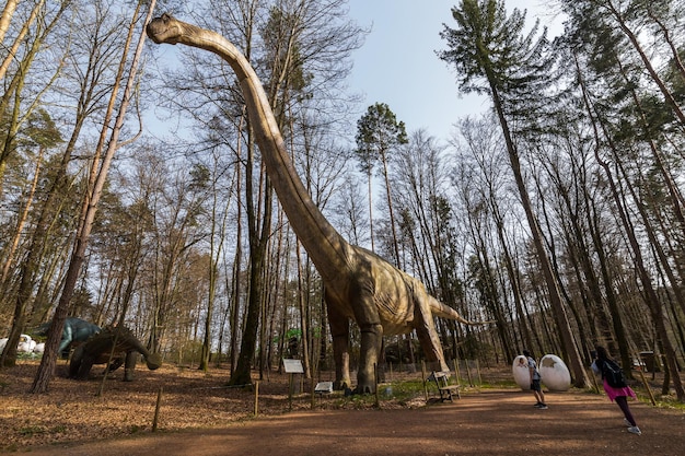 Una enorme réplica alta de un dinosaurio en un bosque