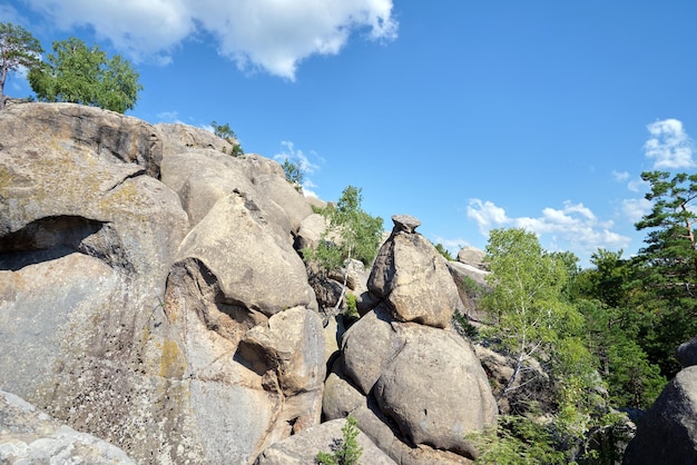 Enormes formações rochosas altas nas montanhas com árvores em crescimento no dia ensolarado de verão