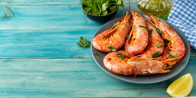 Enormes gambas rojas en un plato sobre fondo azul claro