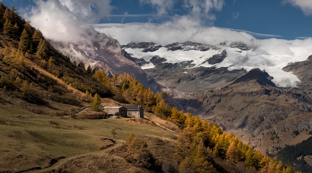 Enormes montanhas nevadas no outono com árvores coloridas