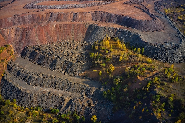 Enormes montes de resíduos de minério de ferro perto da pedreira. Caminhões Belaz dirigindo em fábrica de mineração, pedreira de mina na Ucrânia