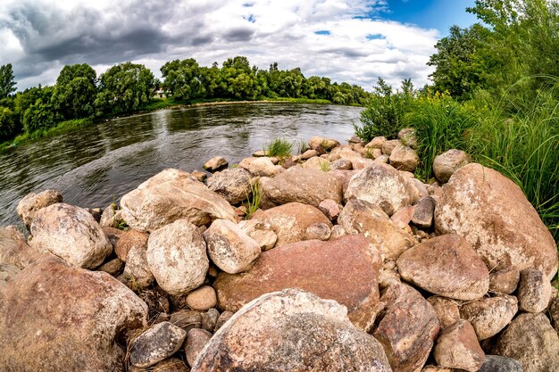 Enormes piedras a orillas de un río ancho en un día nublado