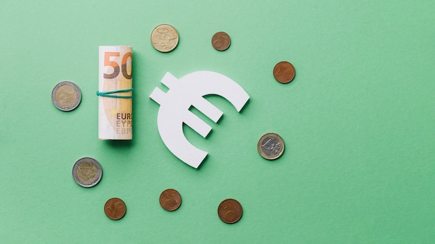 Enrollado billete con monedas y el signo del euro en fondo verde