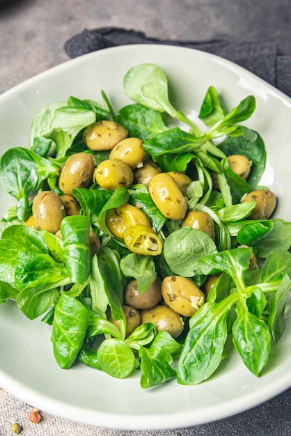 Ensalada de aceitunas, lechuga de hoja verde, lechuga de maíz mache, comida fresca y saludable, dieta de bocadillos en la mesa