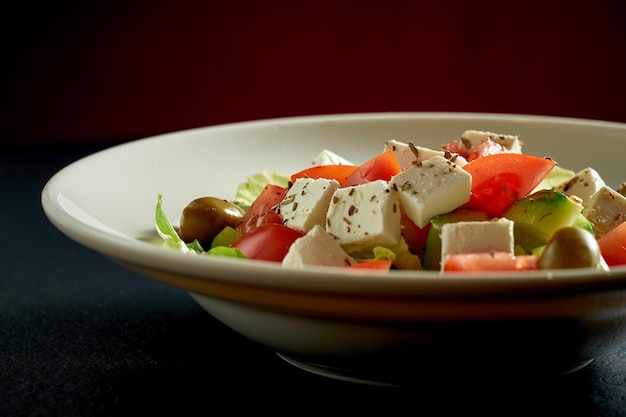 Ensalada con aceitunas, tomates y queso feta en un plato blanco. ensalada griega