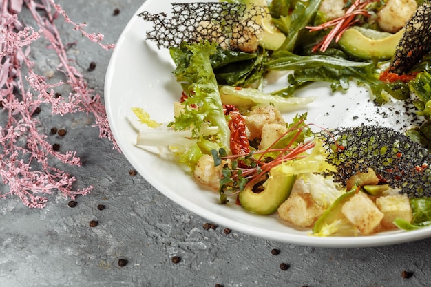 Ensalada de aguacate con espinacas tiernas y granada en un plato negro sobre un fondo de pizarra o hormigón Vista superior con espacio para copiar