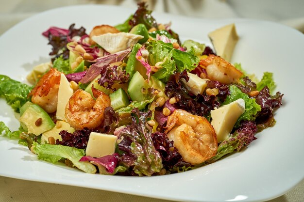 Ensalada de aguacate y gambas en un plato blanco sobre un mantel blanco Luz dura Enfoque selectivo