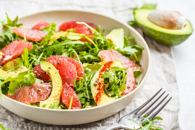 Ensalada del aguacate y del pomelo en una placa blanca en un fondo blanco.