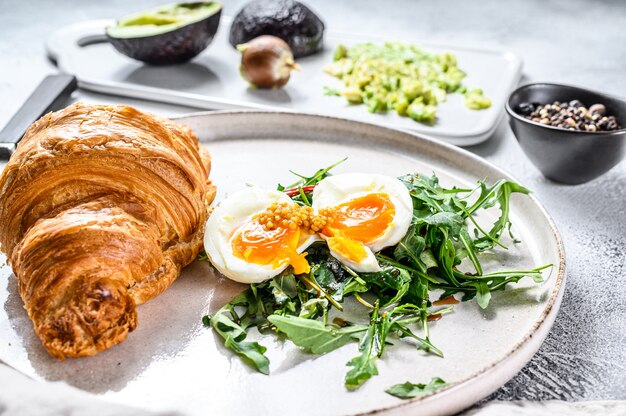 Ensalada de aguacate, rúcula, croissant y huevo.