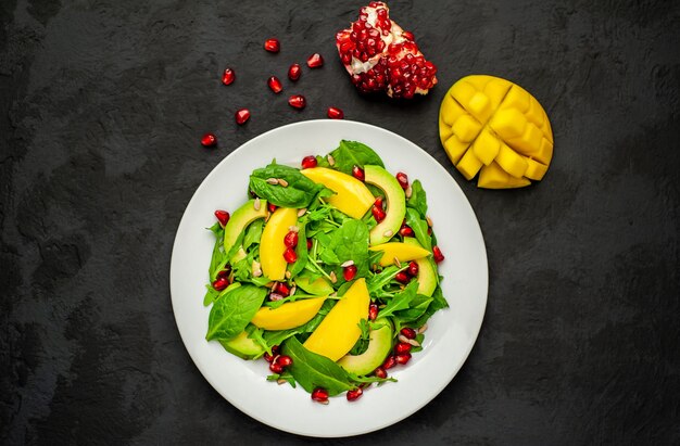 Ensalada con aguacate, rúcula, espinacas, granada, semillas sobre un fondo de piedra