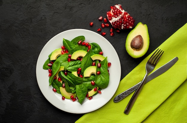 Ensalada con aguacate, rúcula, espinacas, granada, semillas sobre un fondo de piedra