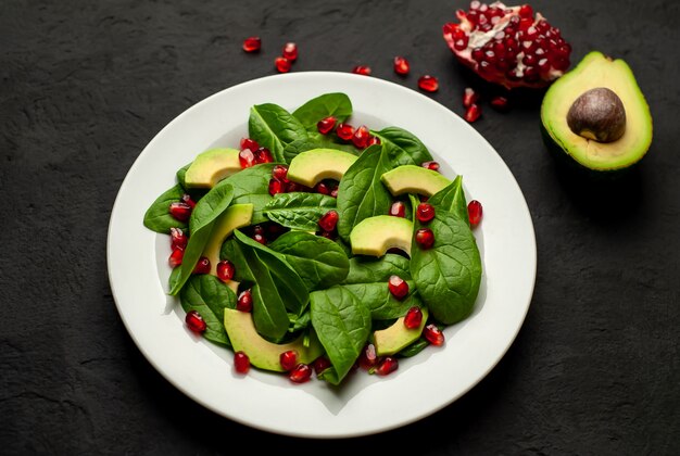 Ensalada con aguacate, rúcula, espinacas, granada, semillas sobre un fondo de piedra