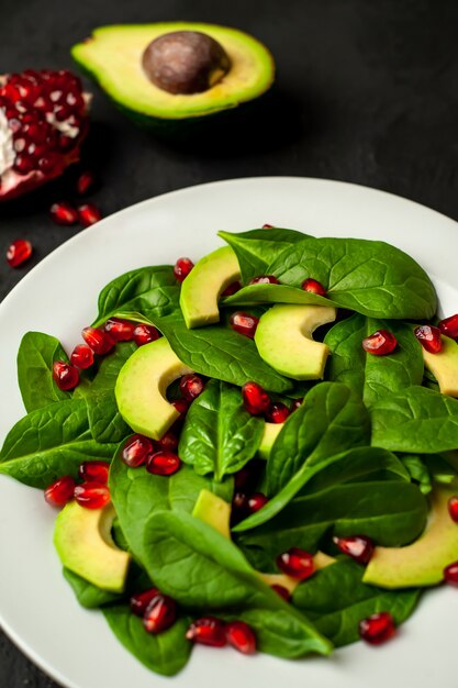 Ensalada con aguacate, rúcula, espinacas, granada, semillas sobre un fondo de piedra