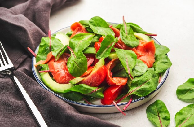 Ensalada de aguacate y salmón, hojas de remolacha, tomates radicchio, aderezo de limón y aceite de oliva para ceto y dieta de tarjeta baja Vista superior de fondo gris