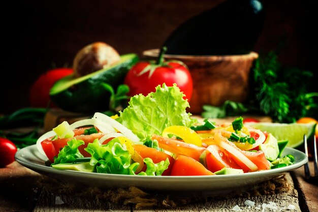 Ensalada con aguacate, salmón, lechuga, cebollas y pimientos en un plato de madera vieja, enfoque selectivo de fondo