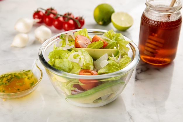 ENSALADA DE AGUACATE saludable con tomate, limón y miel servido en un plato aislado en la vista lateral de fondo gris