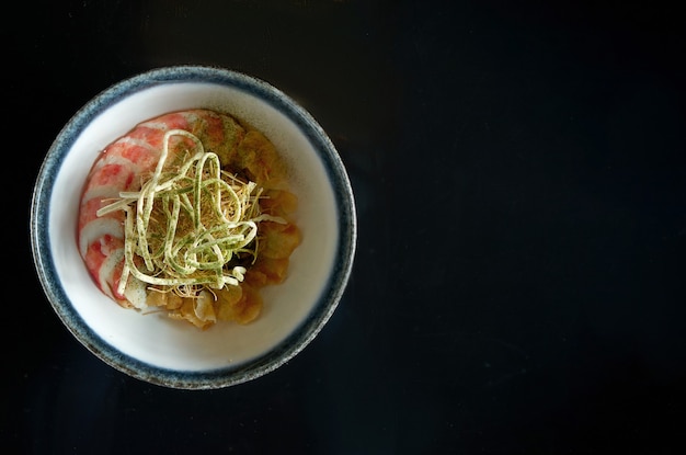 Ensalada de alcachofas con cangrejo y chips de verduras, servida en un cuenco blanco. Aislado en una mesa negra. Comida de restaurante