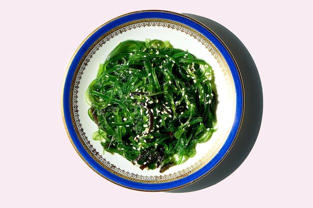 Ensalada de algas wakame con sésamo en un tazón blanco sobre un fondo blanco