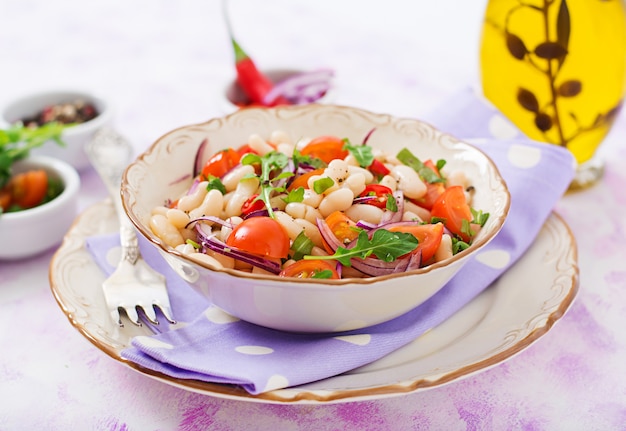 Ensalada de alubias blancas, tomate, rúcula, cebolla roja y pimiento en un tazón.