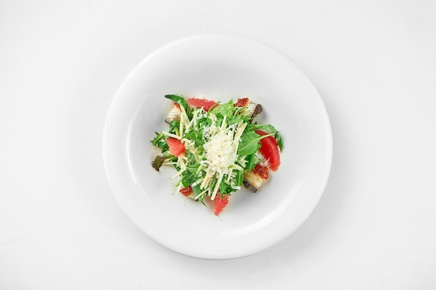 Ensalada con anguila y pomelo en un plato blanco sobre un fondo blanco Primer enfoque selectivo