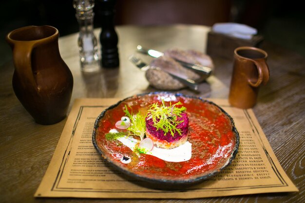 Ensalada con arenque en un plato de cerámica en un restaurante