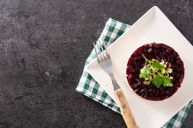 Ensalada de arenque tradicional rusa con remolacha y zanahorias sobre fondo negro