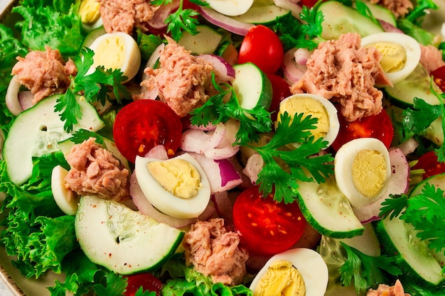 Ensalada de atún ensalada de verduras con huevos de codorniz lechuga cebolla roja y pepinos en una mesa gris claro comida cetogénica estilo de vida alimentación saludable enfoque selectivo vista superior sin gente