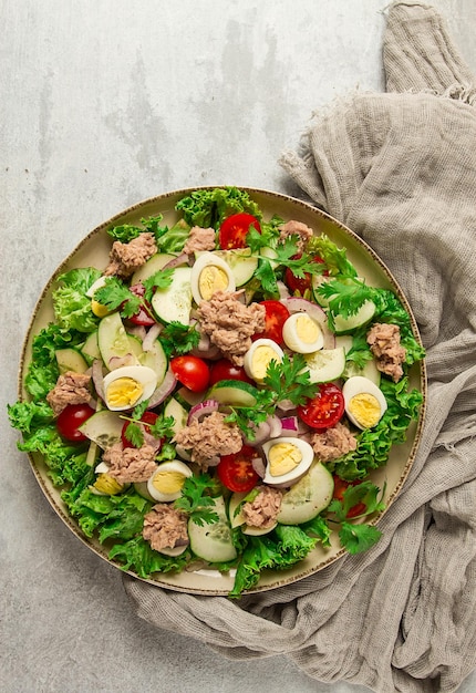 Ensalada de atún ensalada de verduras con huevos de codorniz lechuga cebolla roja y pepinos en una mesa gris claro comida cetogénica estilo de vida alimentación saludable enfoque selectivo vista superior sin gente