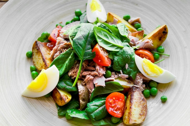 Ensalada de atún con lechuga, huevos y tomates en placa de madera