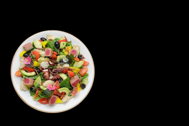 Ensalada con atún de pulpo y verduras sobre un fondo oscuro