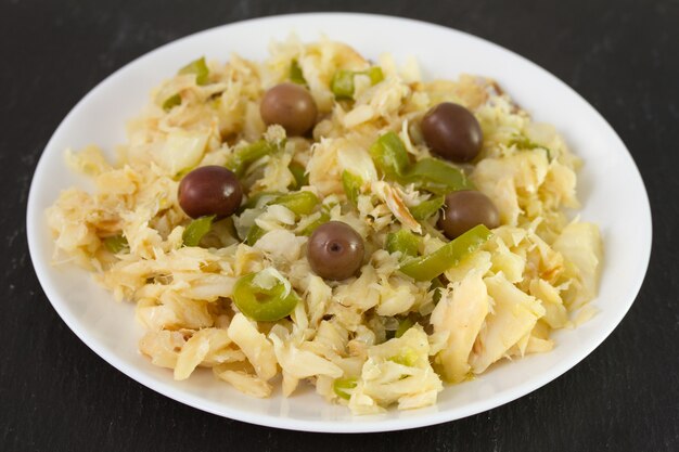 Ensalada de bacalao y verduras en plato blanco