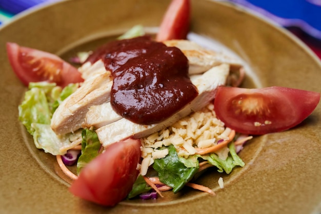 Ensalada barbacoa, con filete de pollo, lechuga, tomates en un plato sobre un fondo de tela mexicana.