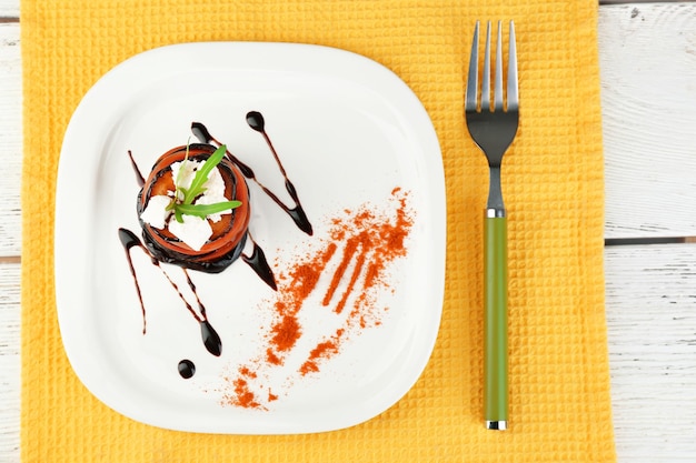 Ensalada de berenjena con tomate y queso feta en plato sobre fondo de madera