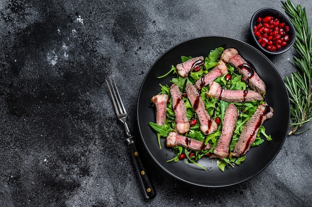 Ensalada de bistec a la parrilla con rúcula, granada y verduras.