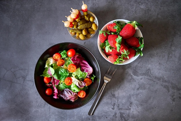 Una ensalada un bol de patatas fritas un bol de brochetas españolas y otro bol de fresas