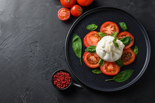 Ensalada de burrata, queso fresco italiano en placa negra.