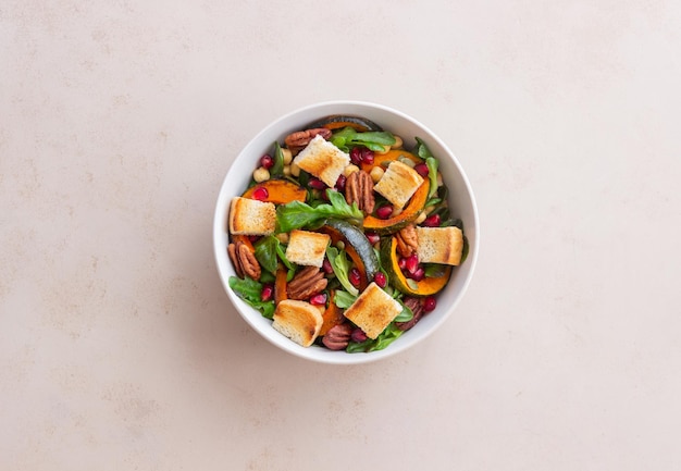 Ensalada con calabaza, granada, pecanas y picatostes. Alimentación saludable. Comida vegetariana.