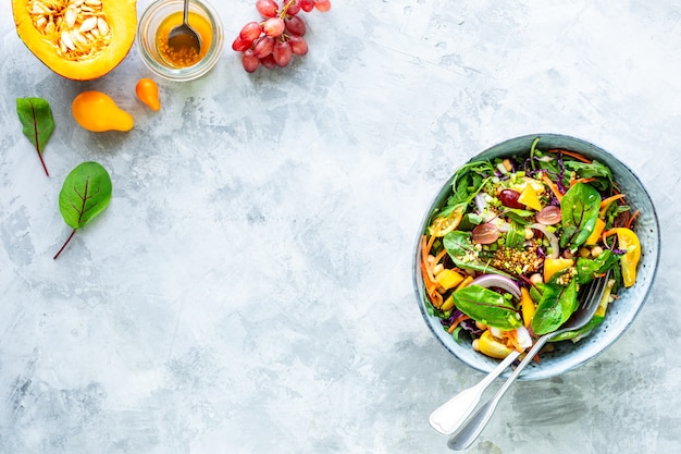 Ensalada de calabaza y verduras frescas en un plato sobre la superficie de piedra blanca