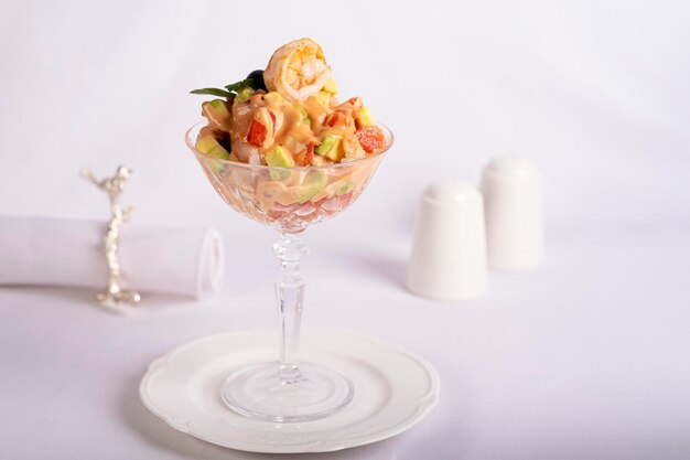 ensalada con camarón en un vaso de cristal en una mesa blanca servida