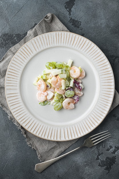 Foto ensalada de camarones, aguacate, langostinos waldorf set, con salsa de manzana y uva, sobre fondo gris, vista superior laicos plana